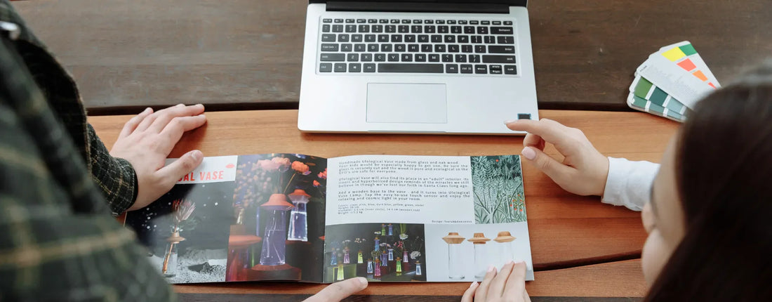 a group of people looking at a brochure and some color pallets in front of a computer reposted by Pixel Profiles