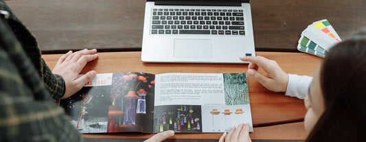 a group of people looking at a brochure and some color pallets in front of a computer reposted by Pixel Profiles